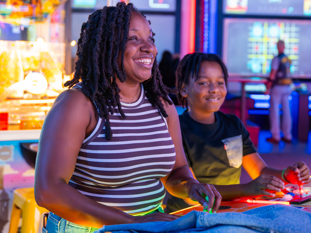 a mom and young boy playing in the arcade